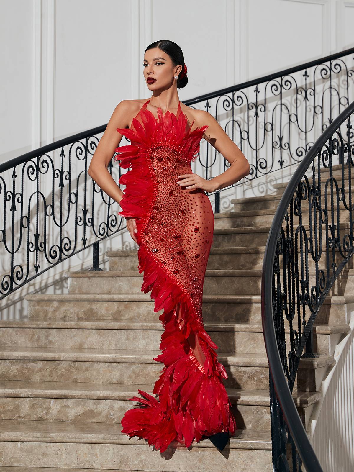 Robe longue rouge en résille ornée de plumes. 